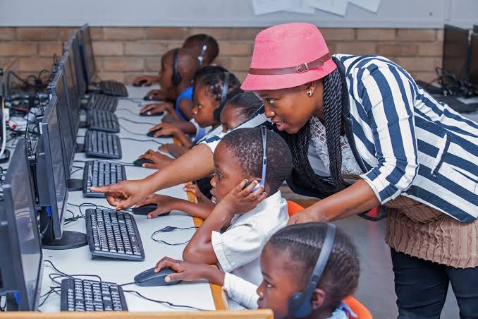 Children learning computer skills with a teacher