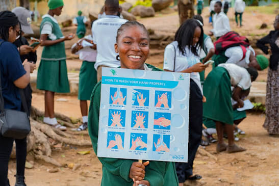 Young advocate holding handwashing instruction poster
